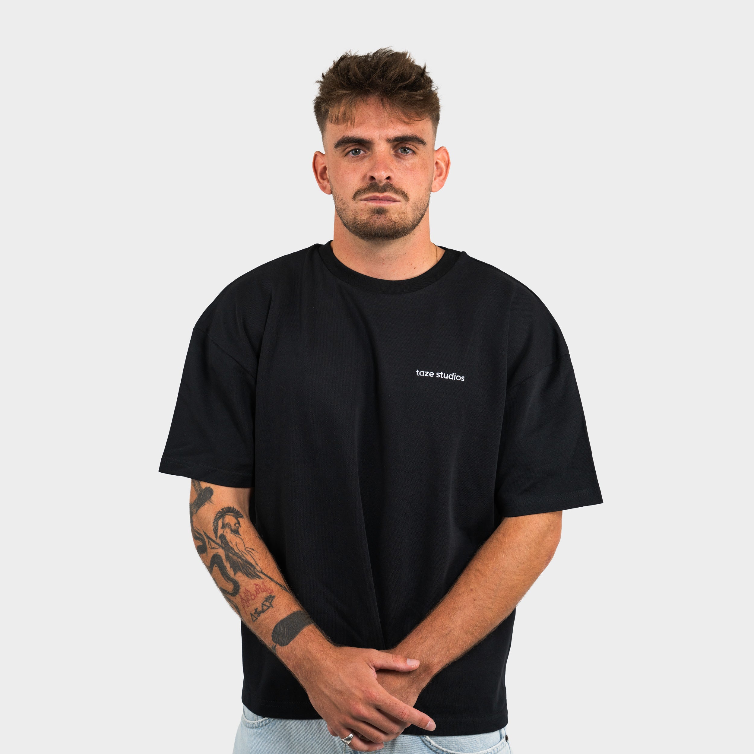 Man wearing a black t-shirt with 'taze studios' logo on a plain background
