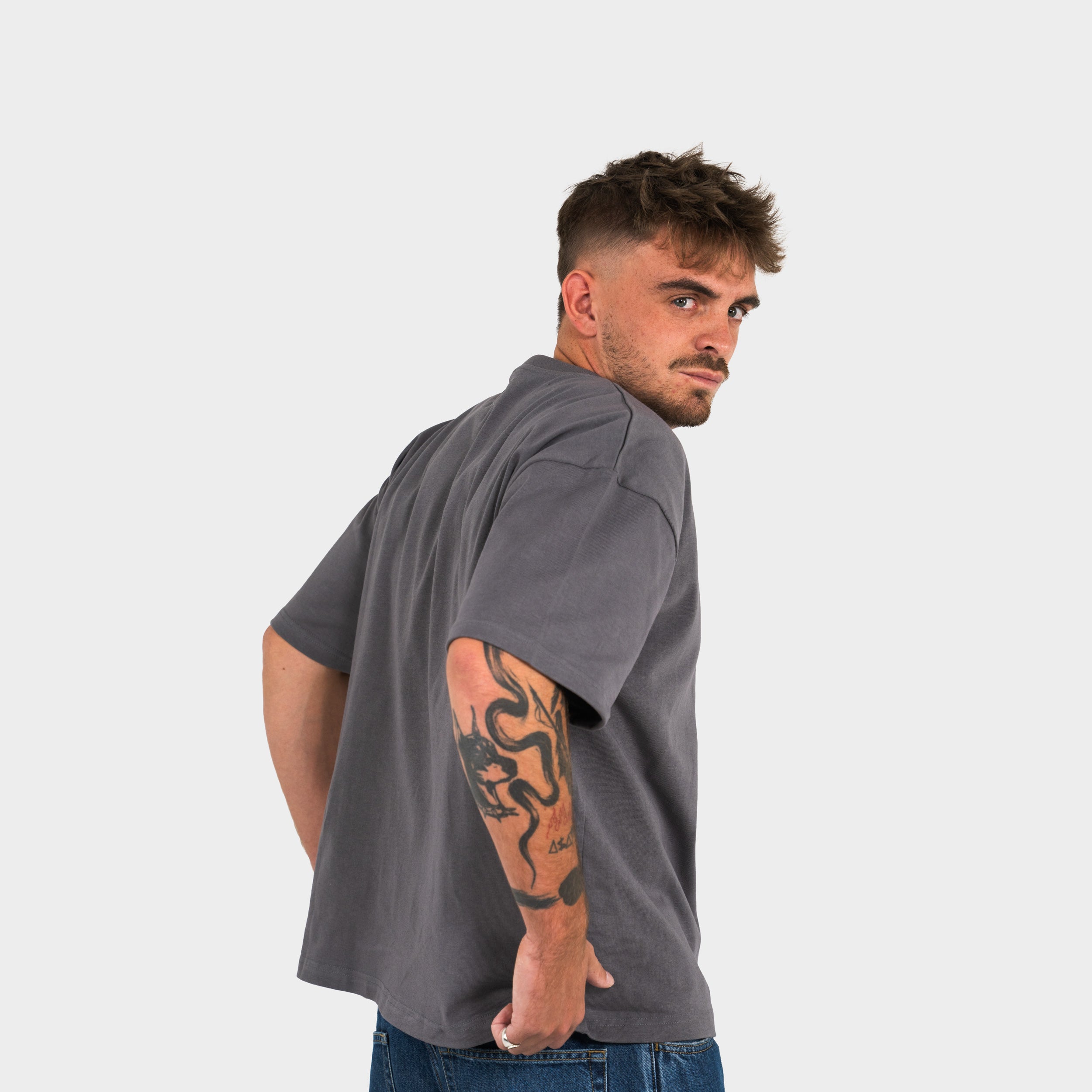 Man wearing a gray 'taze studios' t-shirt on a white background