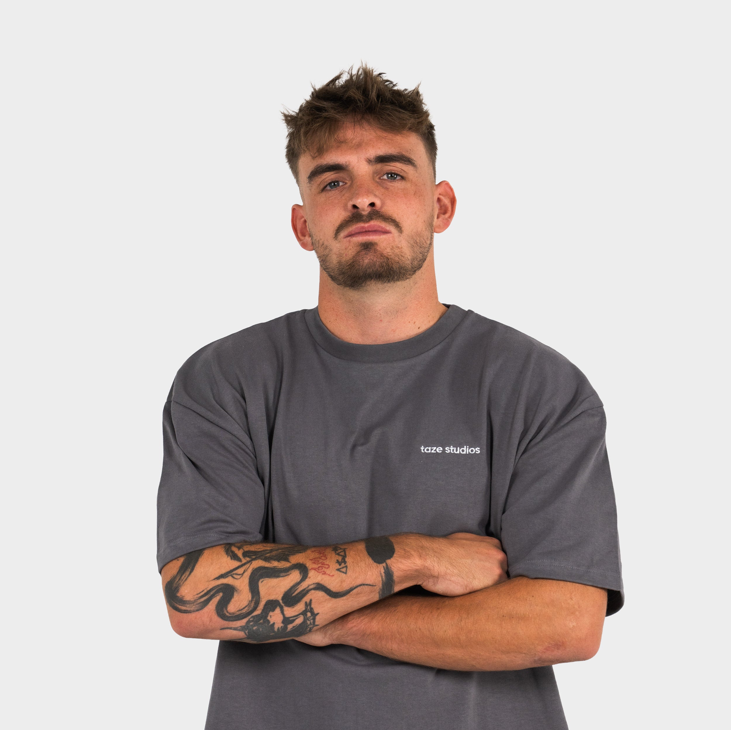 Man wearing a gray t-shirt with 'taze studios' logo on a white background