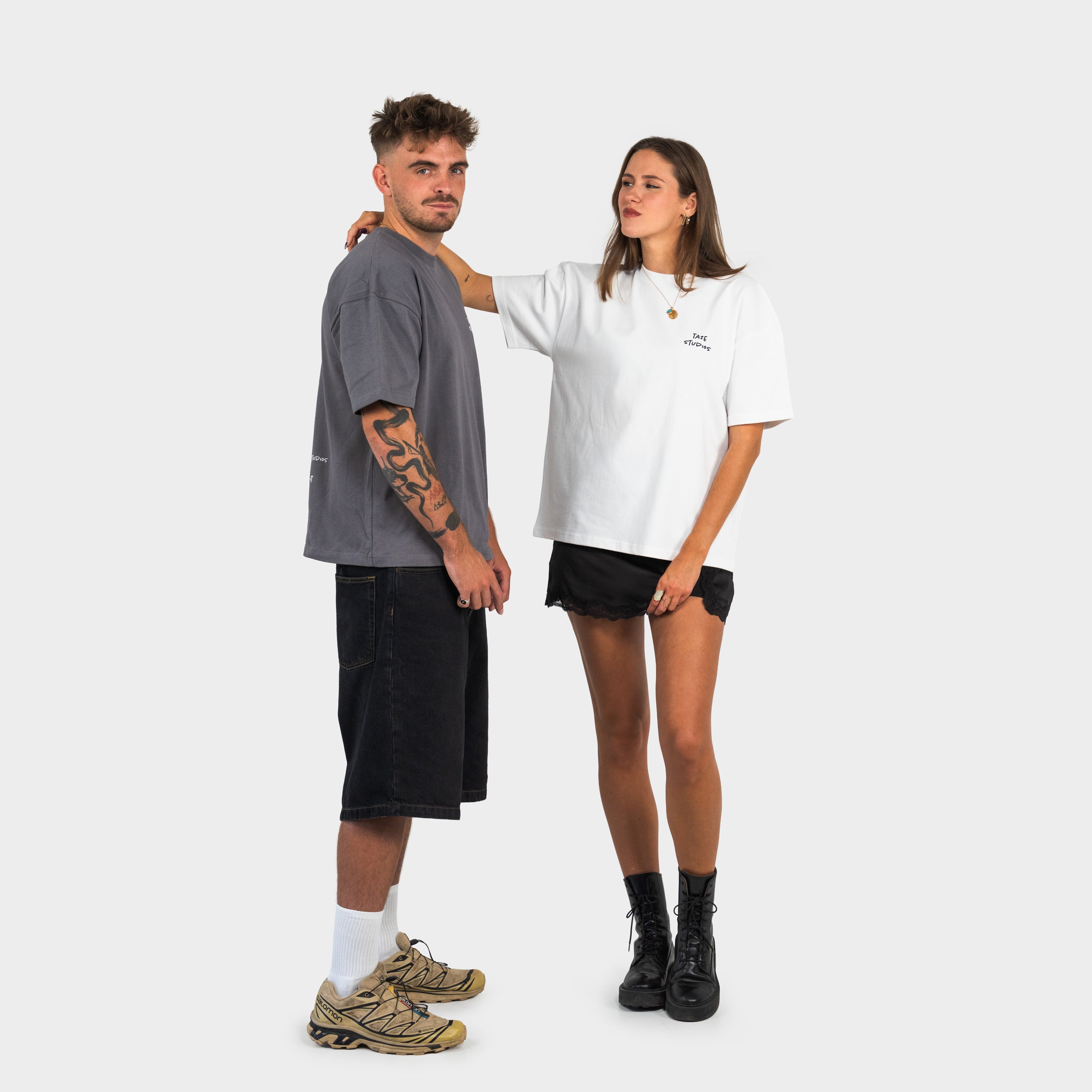 Man and woman standing side by side wearing grey and white t-shirts on a white background